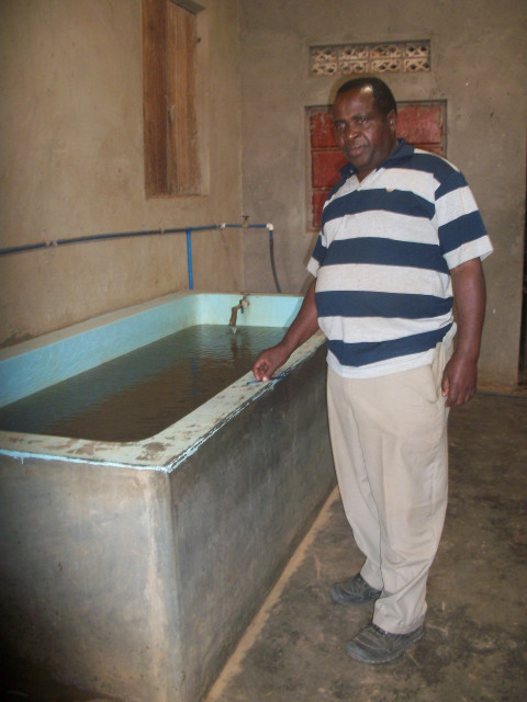 Paul Ssekyewa se tient devant ses casiers à poissons perfectionnés. 